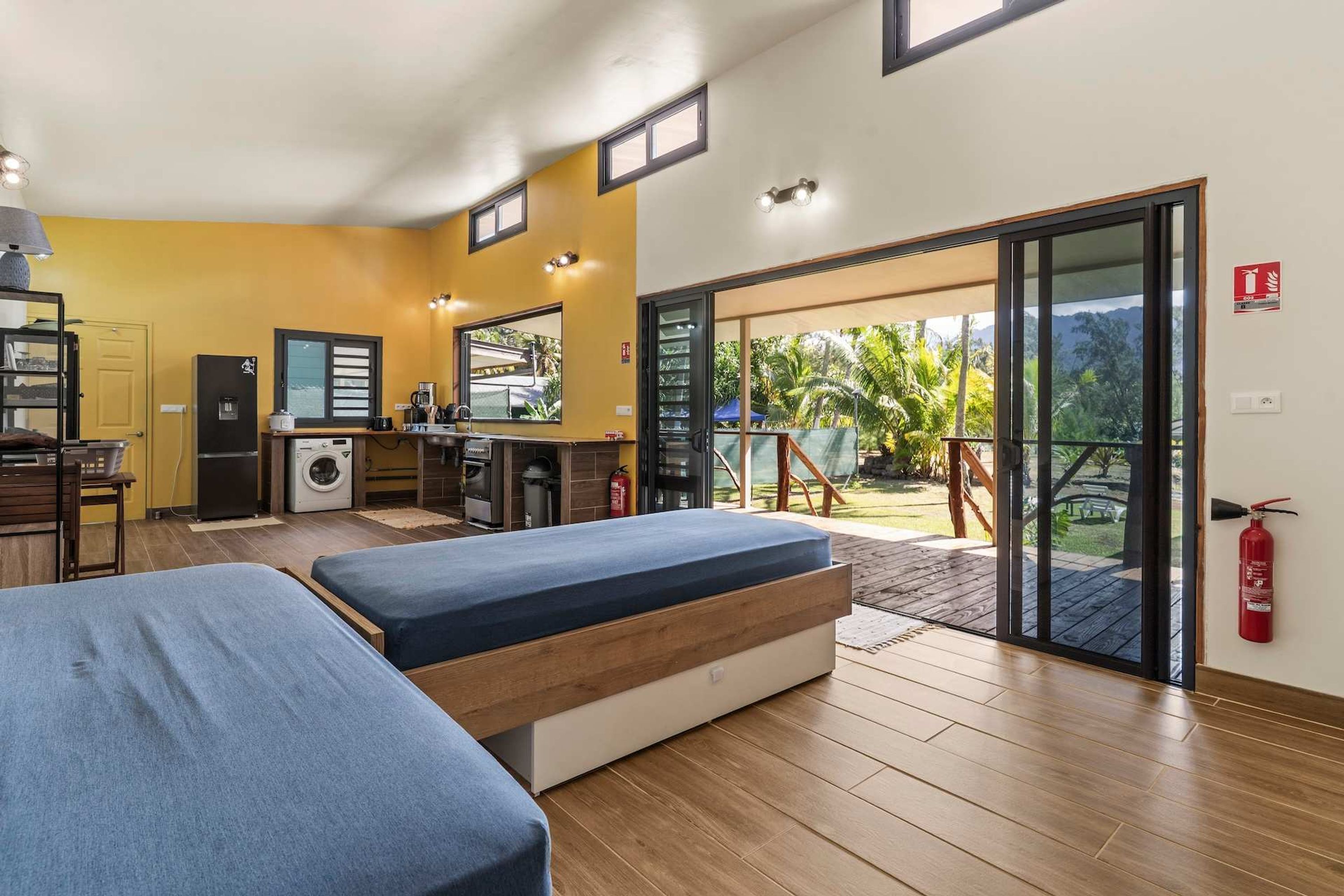 Ein Zimmer mit zwei Betten, einer Küche und einer Glastür zum Balkon.