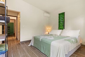 Ein Schlafzimmer mit einem Bett, einer grünen Wanddekoration, einer Lampe und einer Treppe.