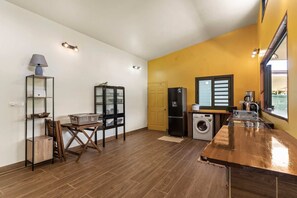 A kitchen with a washing machine, a refrigerator, and a dining area with a table and chairs. - Temenino Villa Komako Seaside House (Taiarapu-Ouest)