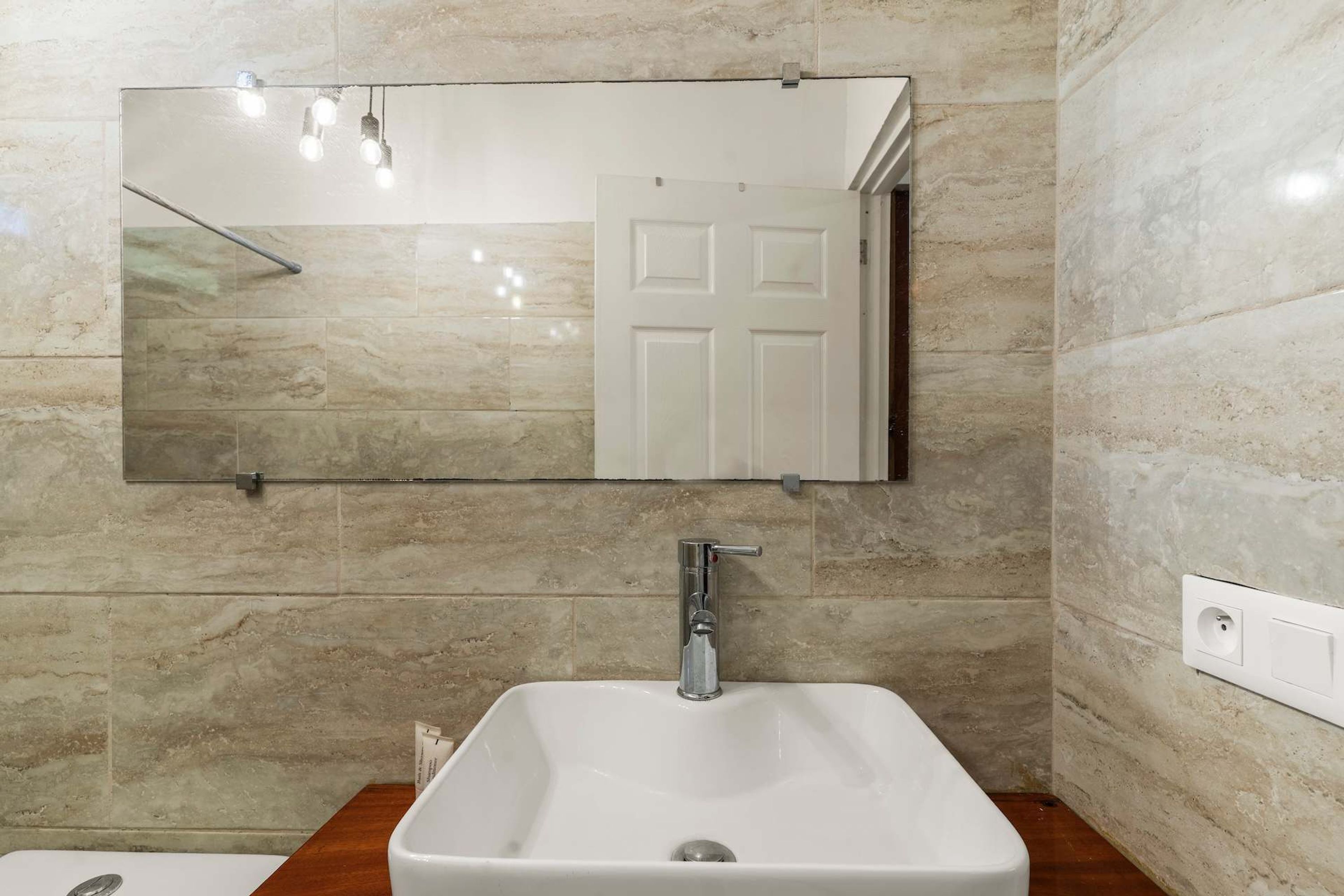 A bathroom with a white sink, a mirror, and a door.