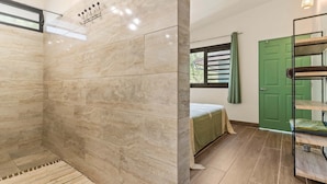 A bathroom with a shower, a bed, a green door, and a bunk bed. - Temenino Villa Komako Seaside House (Taiarapu-Ouest)