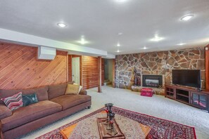 A living room with a stone fireplace, a television, a sofa, and a patterned rug. - Serene 3BR Home in Kent With Modern Comforts (Covington)
