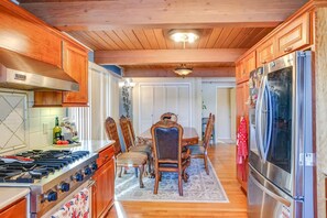 A kitchen with wooden cabinets, a gas stove, a dining table with chairs, and a stainless steel refrigerator. - Serene 3BR Home in Kent With Modern Comforts (Covington)