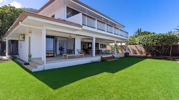 A two-story house with a covered porch, a well-maintained lawn, and a wooden fence.