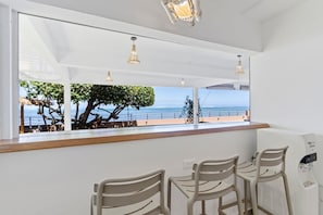 A seating area with a view of the sea, a wooden counter, and a water dispenser. - Spacious 3BR Oceanfront Retreat Paea Tahiti (Paea)
