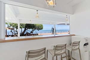 Un área de estar con vista al mar, una barra de madera y un dispensador de agua.