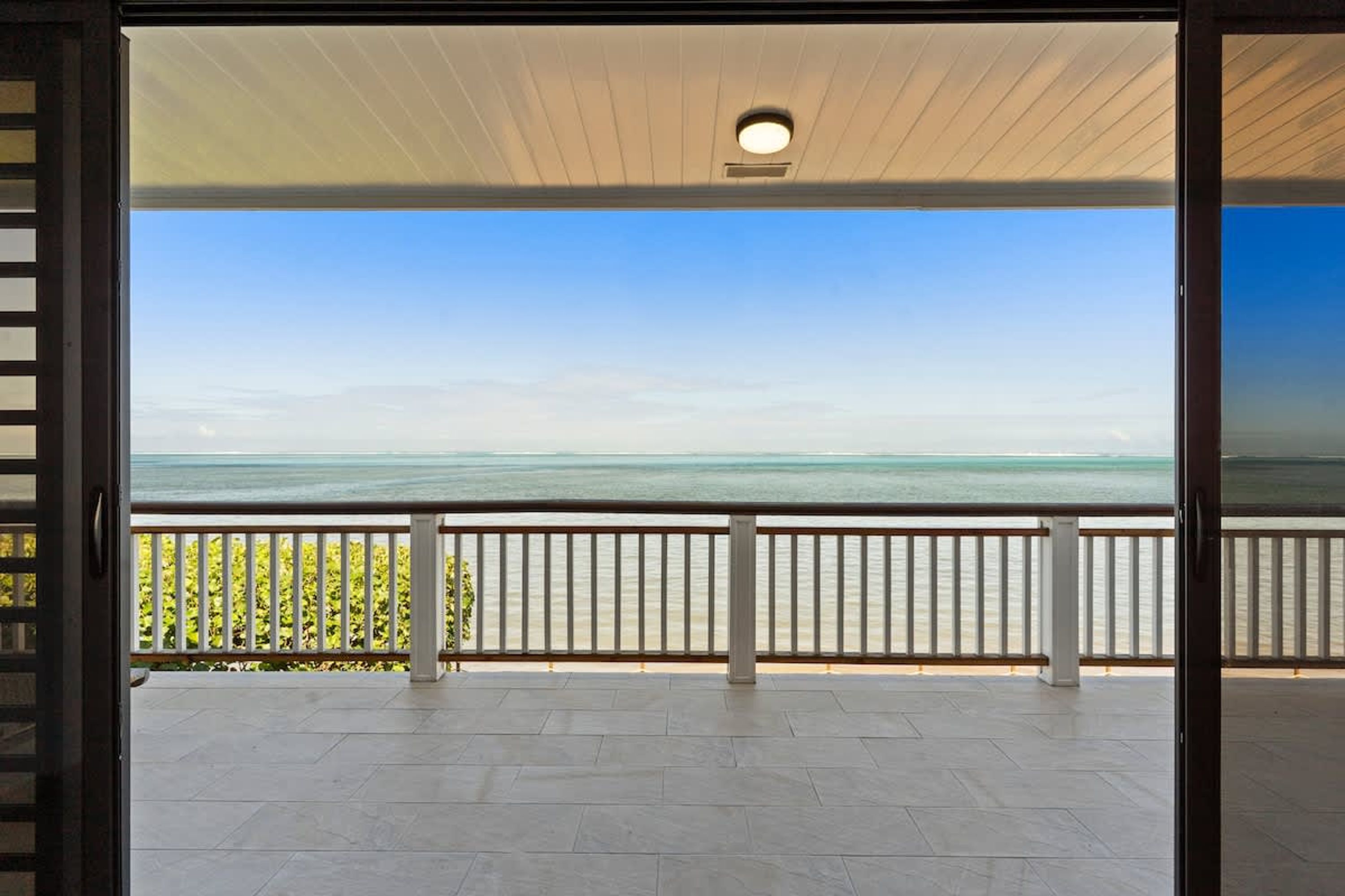 A balcony with a view of the sea, a ceiling light, and a railing.