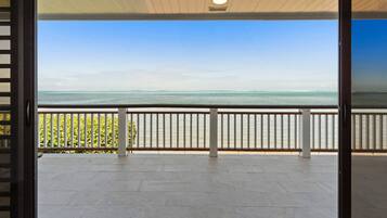 A balcony with a view of the sea, a ceiling light, and a railing.