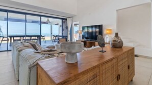 Un salon moderne doté d’une grande fenêtre, d’une table basse en bois et d’un téléviseur à écran plat.
