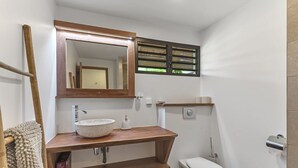 Un baño con tocador de madera, un espejo grande, un inodoro y un perchero para toallas.