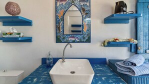 A bathroom with a white sink, blue shelves, a decorative mirror, and a blue wall. - Seaside Air-conditioned Bungalow Tamara (Moorea-Maiao)