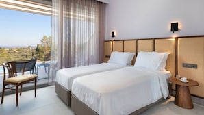 Una camera d'albergo con due letti, una sedia, un tavolino e vista sull'esterno.