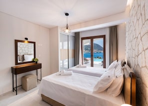 A hotel room with a bed, a desk, a mirror, and a view of the sea. - Villa Unique in Lefkada (Lefkada)