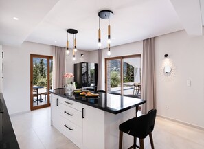 Una cucina moderna con isola centrale, illuminazione a sospensione e vista sull'esterno.