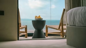 A room with a view of the sea, a round table with a bowl of fruit, and two wicker chairs. - Orizontas 1 Syvota in Igoumenitsa (Igoumenitsa)