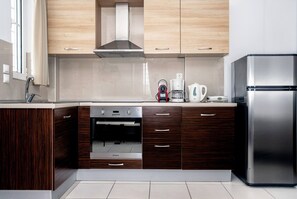 Eine moderne Küche mit Holzausstattung, einem Edelstahlkühlschrank, einem Einbauofen und einer Kaffeemaschine.