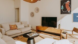 A living room with a sofa, coffee table, TV, and artwork on the wall. - FR Villa Mulberry in Sivota (Lefkada)