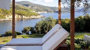 A lounge chair with a view of a lake and hills. - Zavia Villa Alpha 2B Syvota (Igoumenitsa)