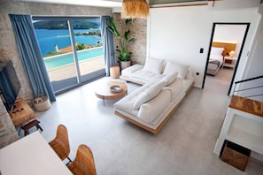 A modern living room with a sofa, a coffee table, and a view of the sea. - Smirties Villa Haris 2bed (Lefkada)