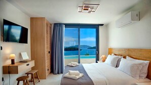 A modern hotel room with a bed, a desk, a TV, and a view of the sea. - Smirties Villa Haris 2bed (Lefkada)