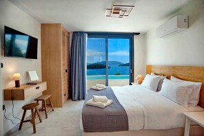 A modern hotel room with a bed, a desk, a TV, and a view of the sea. - Smirties Villa Haris 2bed (Lefkada)