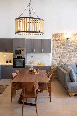 Una cucina moderna con mobili grigi, un tavolo da pranzo in legno e una parete d'accento in pietra.