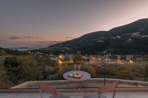 Ein Balkon mit Tisch für zwei Personen, mit Blick auf eine Berglandschaft und eine Stadt.