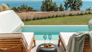 A poolside view with lounge chairs, a table with drinks, and a view of the sea. - Orizontas 3 Syvota in Igoumenitsa (Igoumenitsa)