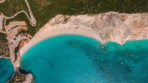 An aerial view of a coastal area with a beach, a road, and scattered buildings. - Desimi Villa Luca in Lefkada (Lefkada)