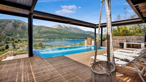 A pool with a view of mountains and a lake, wooden deck, and outdoor furniture. - Desimi Villa Luca in Lefkada (Lefkada)