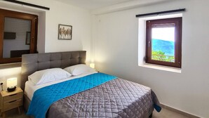Een slaapkamer met een bed, bedlampjes, een raam met uitzicht en een plafondlamp.