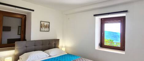 A bedroom with a bed, bedside lamps, a window with a view, and a ceiling light.