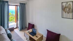 Een moderne woonkamer met een bank, een houten salontafel met een laptop en een uitzicht door een glazen deur.