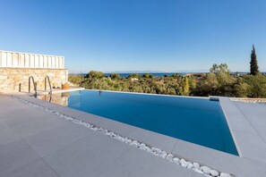 A swimming pool with a stone wall and a view of the landscape. - Z4 Bita 1bed in Frini (Lefkada)