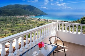 A balcony with a table, chair, and a vase with flowers. - Dream Villa in Ponti (Lefkada)