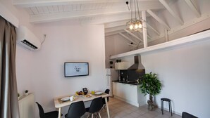 A modern kitchen with white cabinets, a black countertop, and a hanging light fixture. - Drakatos K Apartment (Lefkada)