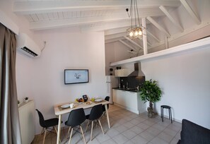 A modern kitchen with white cabinets, a black countertop, and a hanging light fixture. - Drakatos K Apartment (Lefkada)