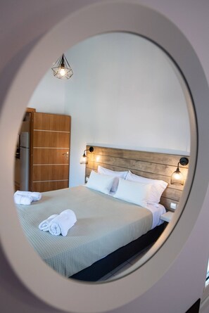 Ein Rundblick auf ein Hotelzimmer mit einem Bett, einem Holzschrank und einer Pendelleuchte.