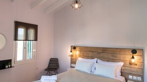A bedroom with a bed, a chair, a window, and a hanging light fixture. - Drakatos K Apartment (Lefkada)