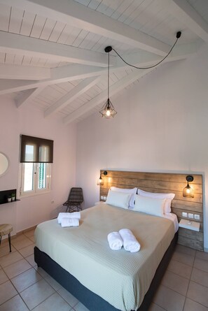 A bedroom with a bed, a chair, a window, and a hanging light fixture. - Drakatos K Apartment (Lefkada)