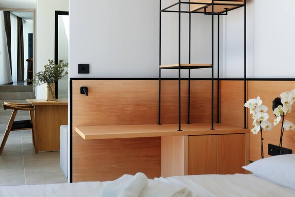 Un dormitorio moderno con un escritorio de madera, una cama y una pequeña estantería.