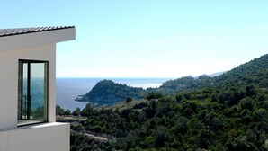 A modern building with a large window overlooking a coastal landscape. - Scirocco Telemachos 1 BED (Lefkada)