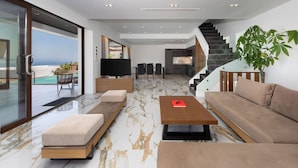 Un salon moderne avec un canapé, une table basse, un téléviseur et un escalier menant à un balcon.