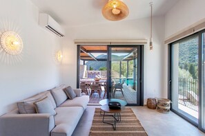 A modern living room with a sofa, a coffee table, and a dining area with chairs and a table. - Desimi Villa Naya in Desimi (Lefkada)