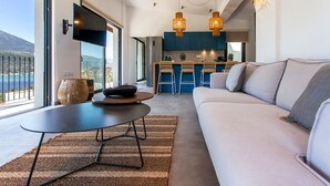 Ein modernes Wohnzimmer mit Sofa, einem Esstisch und einer Küche im Hintergrund.