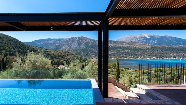 Ein Pool mit Blick auf die Berge, eine Holzterrasse und ein klarer Himmel.