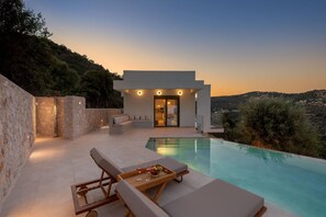 Een moderne villa met een zwembad, terras en uitzicht op het omliggende landschap.