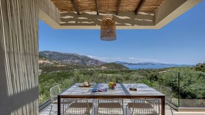 A terrace with a table and chairs, overlooking a scenic landscape. - Villa Eptanisa in Sivota (Lefkada)