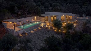A modern villa with a swimming pool, outdoor seating, and a stone retaining wall. - Villa Eptanisa in Sivota (Lefkada)