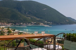 A table with two chairs, overlooking a coastal view with mountains and a beach. - Aria 3 Mare in Ponti (Lefkada)